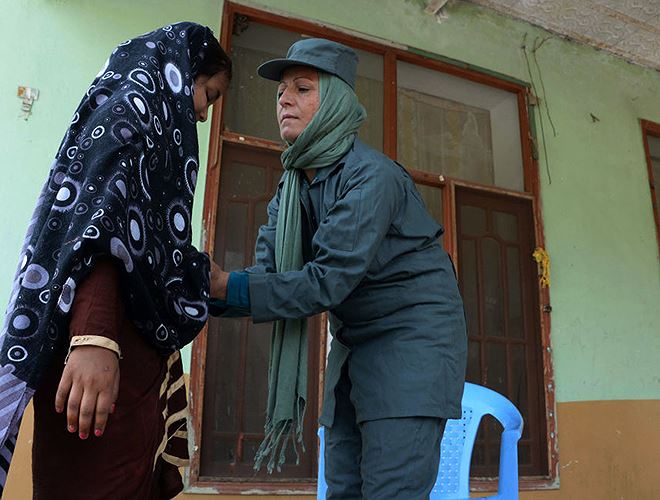 Nữ sĩ quan Cảnh sát Afghanistan Zakira (bên phải), 32 tuổi kiểm tra trang phục một phụ nữ tại sân vận động Sherzai ở Jalalabad